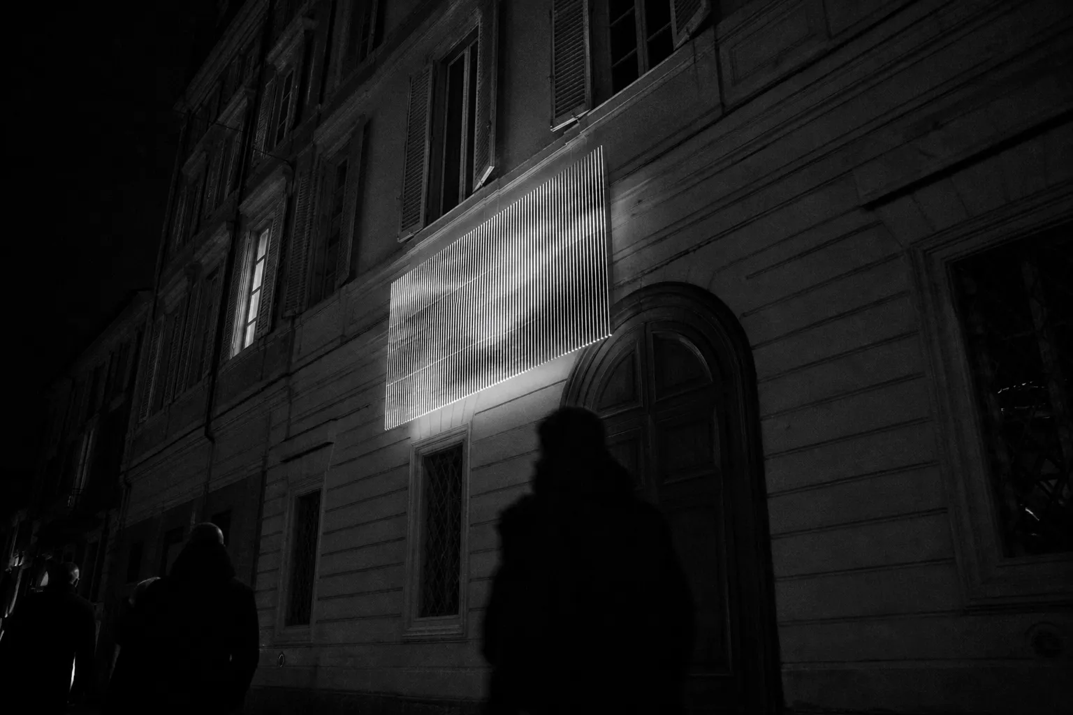 Facciata urbana di notte con un’installazione discreta, in bianco e nero